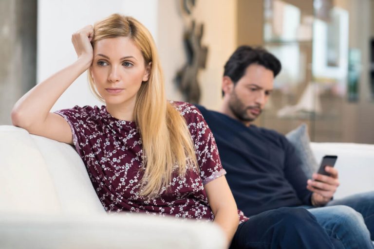 Divorce as a Leadership Transition: A Smarter Way for Professional Women to Navigate It Couple sitting on couch, with woman's back turned away from partner - relationship challenges.